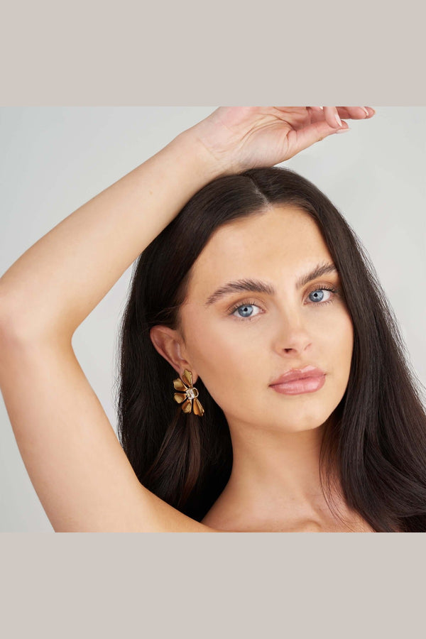 Close-up of a model wearing gold-plated Camille Crystal Bloom Earrings featuring floral design and crystals.