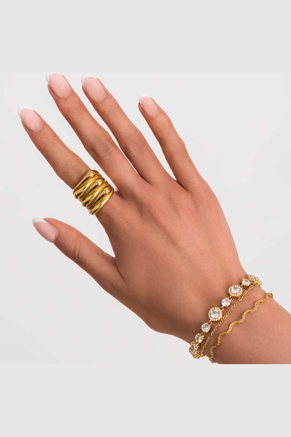 Close-up of a hand wearing a gold ring and an Amira Gold Diamante Tennis Bracelet with sparkling stones.