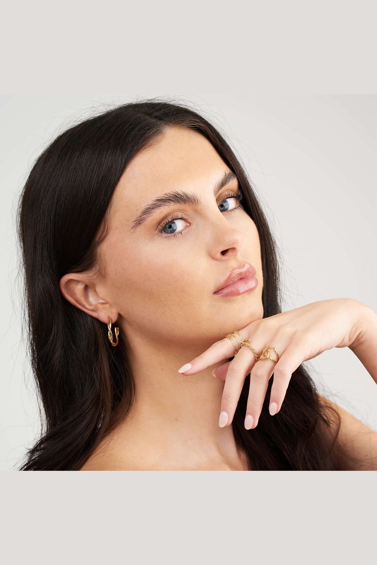 Close-up of a model showcasing Ayla Twist Band Ring and gold hoop earrings, emphasizing elegant jewelry styling.