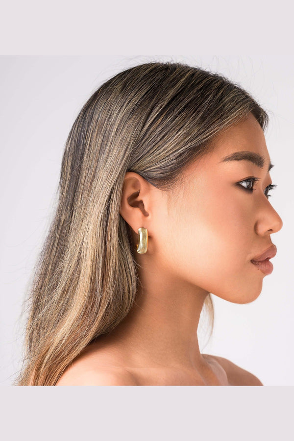 Profile view of a model wearing ARIIRA Selene Ribbed Hoop Earrings, showcasing their gold ribbed design and polished finish.