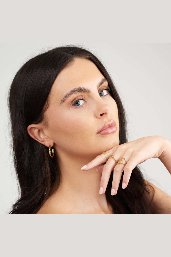 Close-up of a model showcasing Ayla Twist Band Ring and gold hoop earrings, emphasizing elegant jewelry styling.