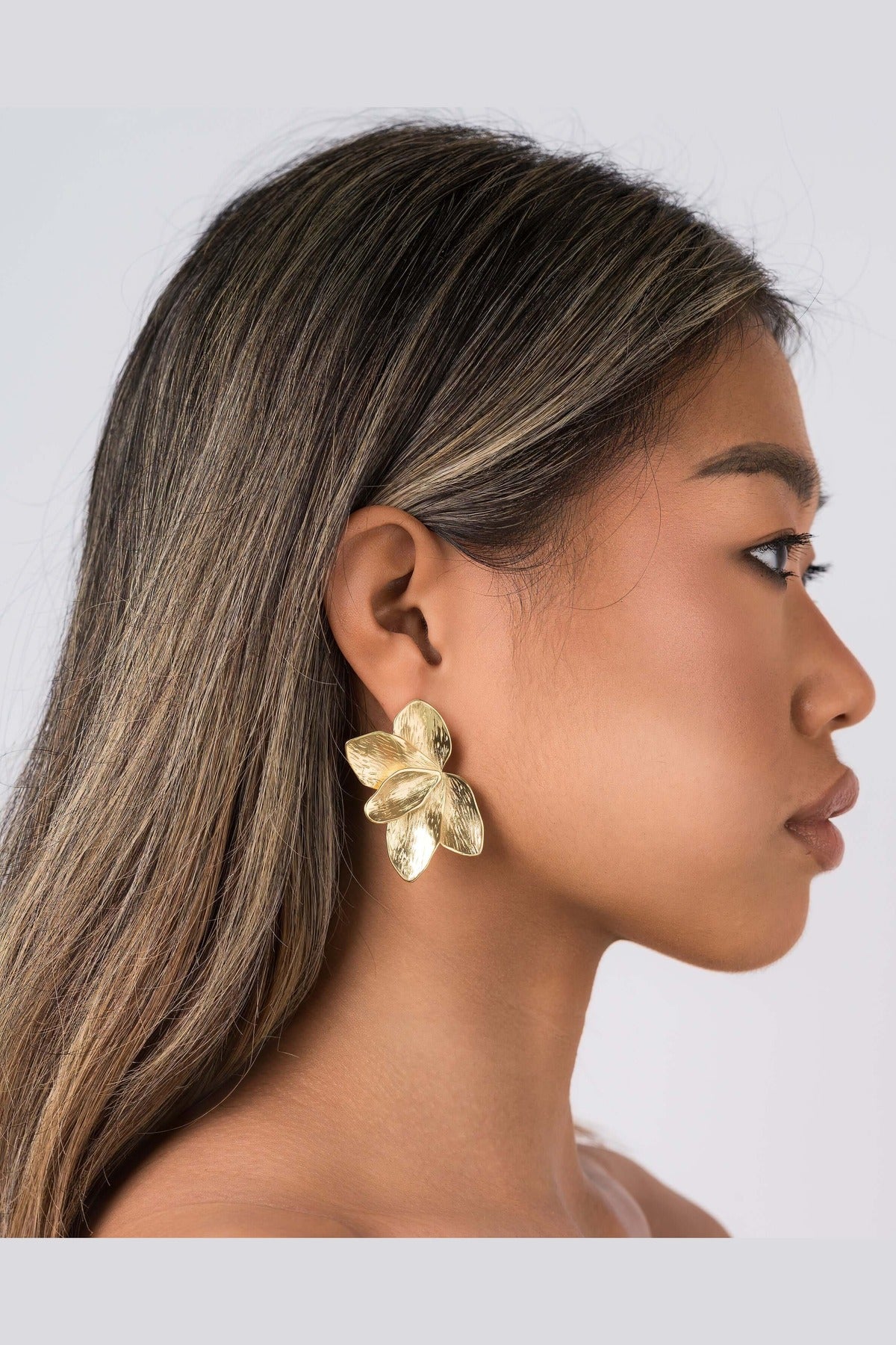 Flora Textured Bloom Stud Earrings by ARIIRA, showcasing a model wearing elegant gold floral studs.