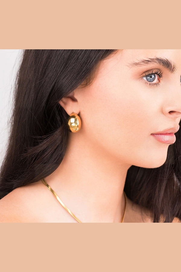 Sana Gold Sculpted Dome Earrings worn by a model, showcasing their polished gold finish and elegant design.