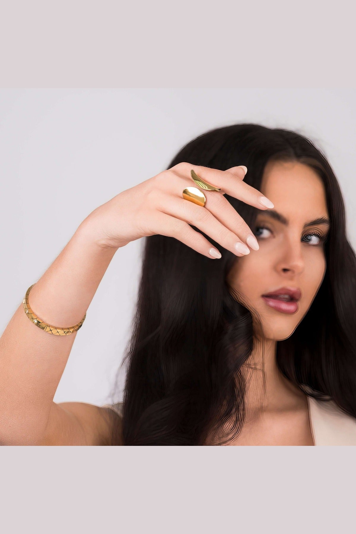 A woman showcasing the Elena Sculpted Leaf Statement Ring by ARIIRA, highlighting its elegant design and shine.
