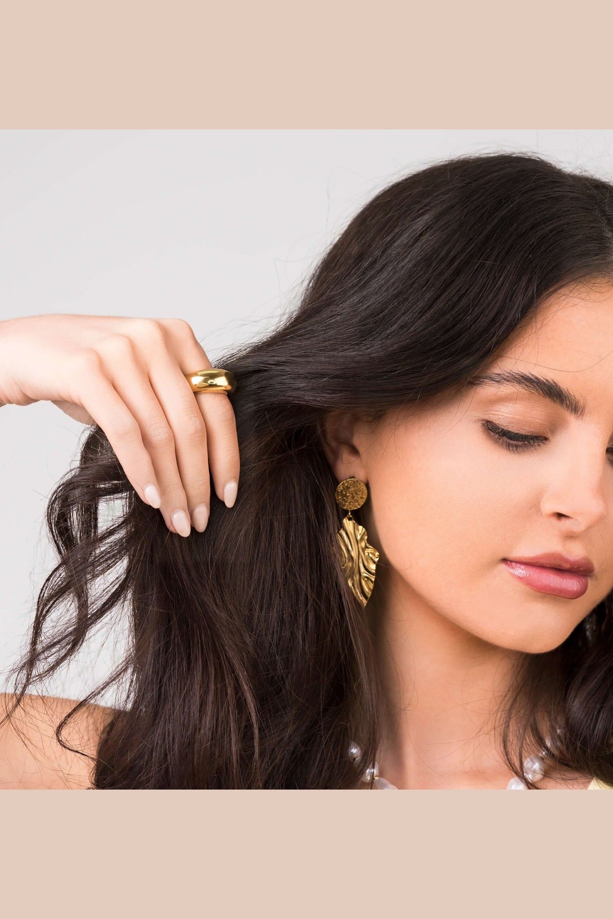 Close-up of a woman wearing the Noura Dome Band Ring and statement earrings, showcasing a stylish jewelry look.