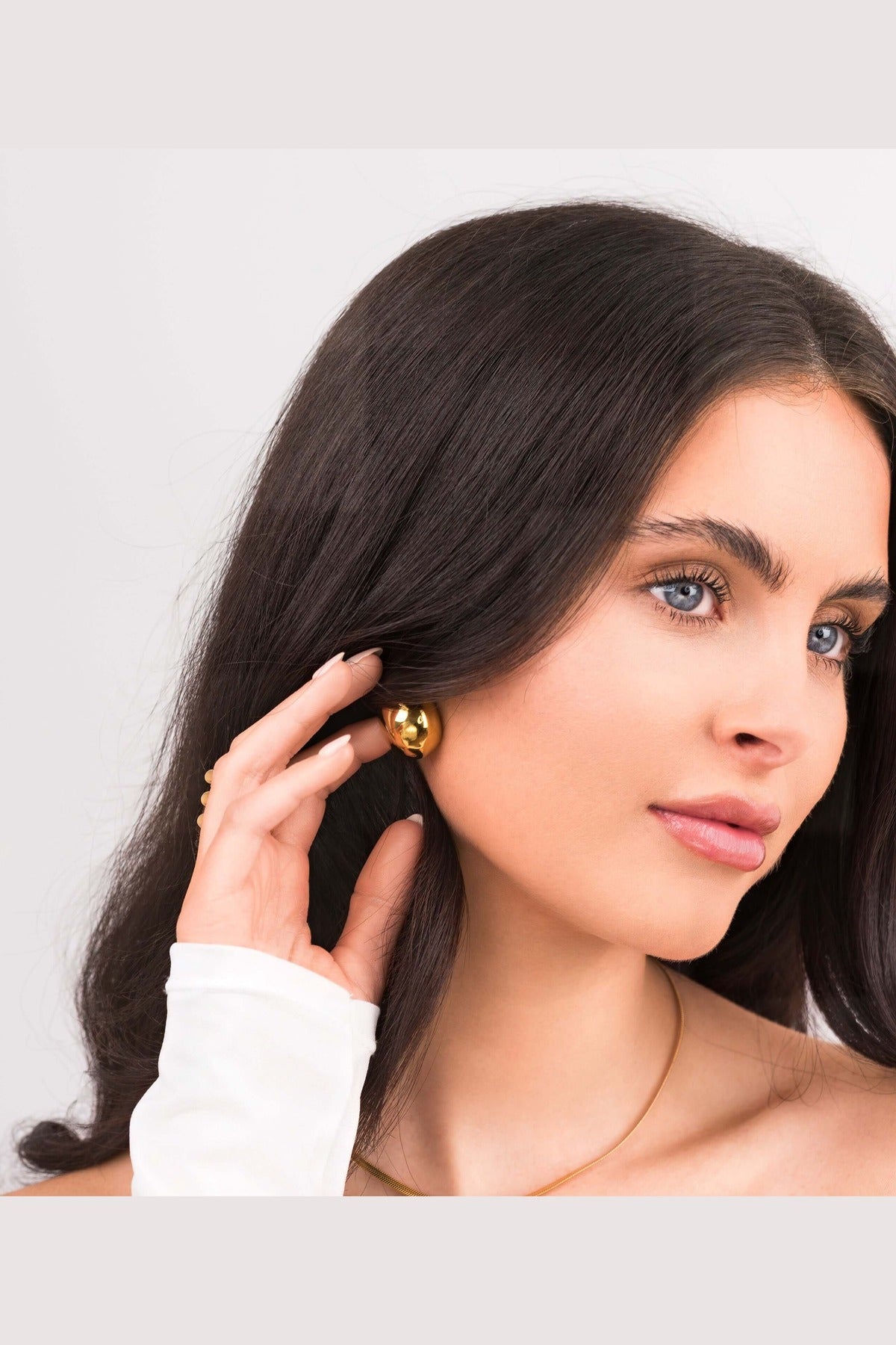 Model wearing ARIIRA Sana Gold Sculpted Dome Earrings, showcasing elegant gold-plated studs with a modern silhouette.