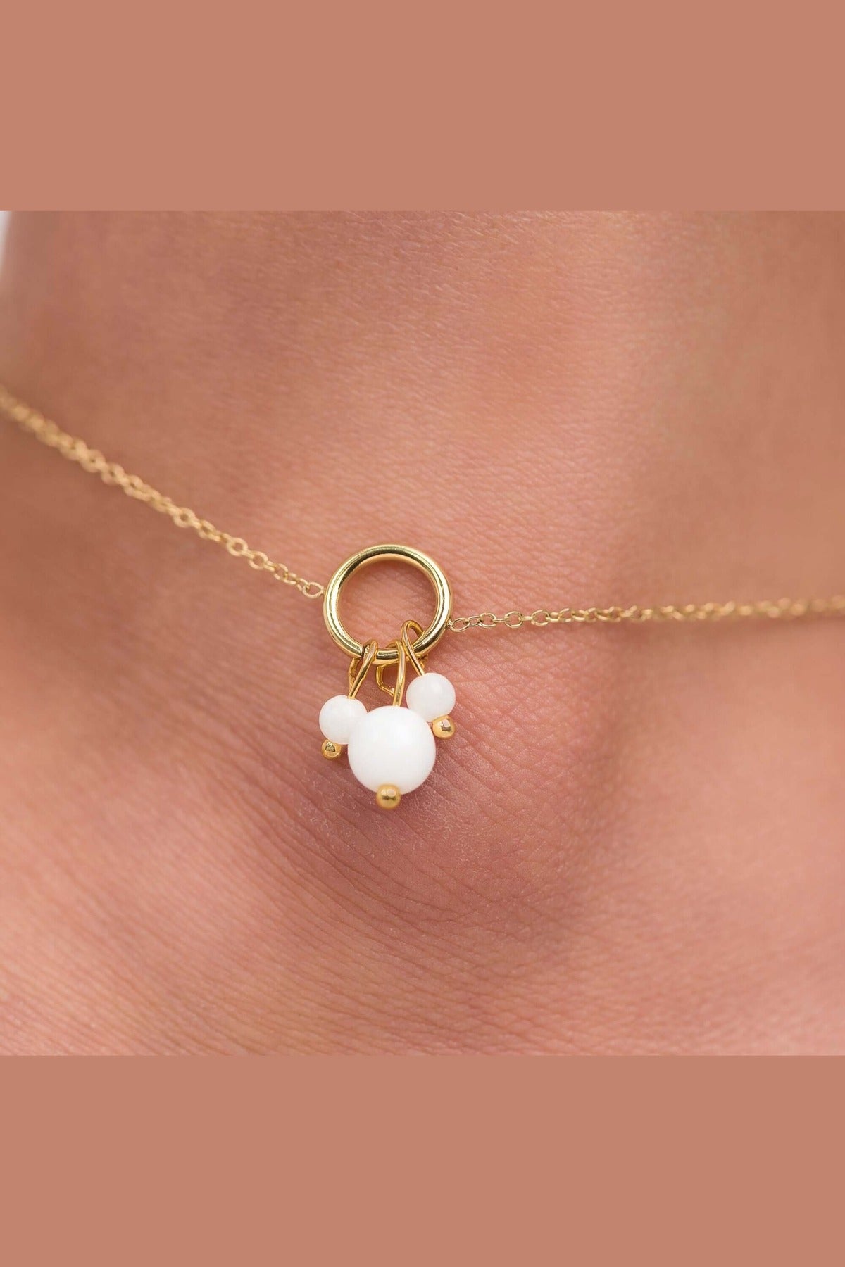 Close-up of a delicate gold-plated anklet featuring pearl-like charms, showcasing elegance and femininity.